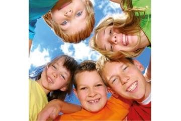 Fünf Kinder stehen im Kreis und schauen nach unten in die Kamera