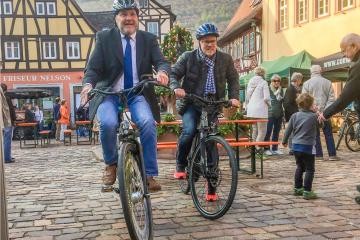Bürgermeister Frank Volk und sein Amtskollege aus Bammental, Holger Karl, fahren auf dem Marktplatz mit Pedelecs.