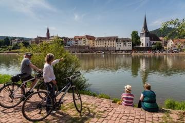Zwei Fahrradfahrer schauen vom Kleingemünder Ufer aus auf die Ansicht der Altstadt