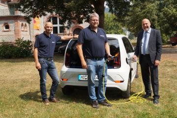Bürgermeister Frank Volk und seine Mitarbeiter begutachten im Menzerpark das neue E-Auto der Stadt