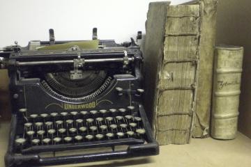 Eine alte Schreibmaschine neben antiken Büchern im Stadtarchiv