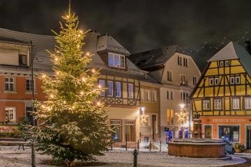 nächtlicher Marktplatz mit geschmücktem Weihnachtsbaum