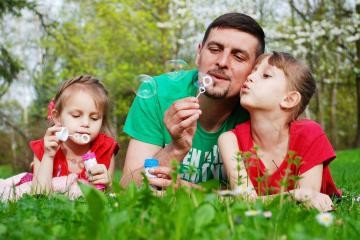 Mann macht mit 2 Mädchen Seifenblasen