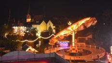 Beleuchtetes Karussell auf dem Bohrermarkt bei Nacht